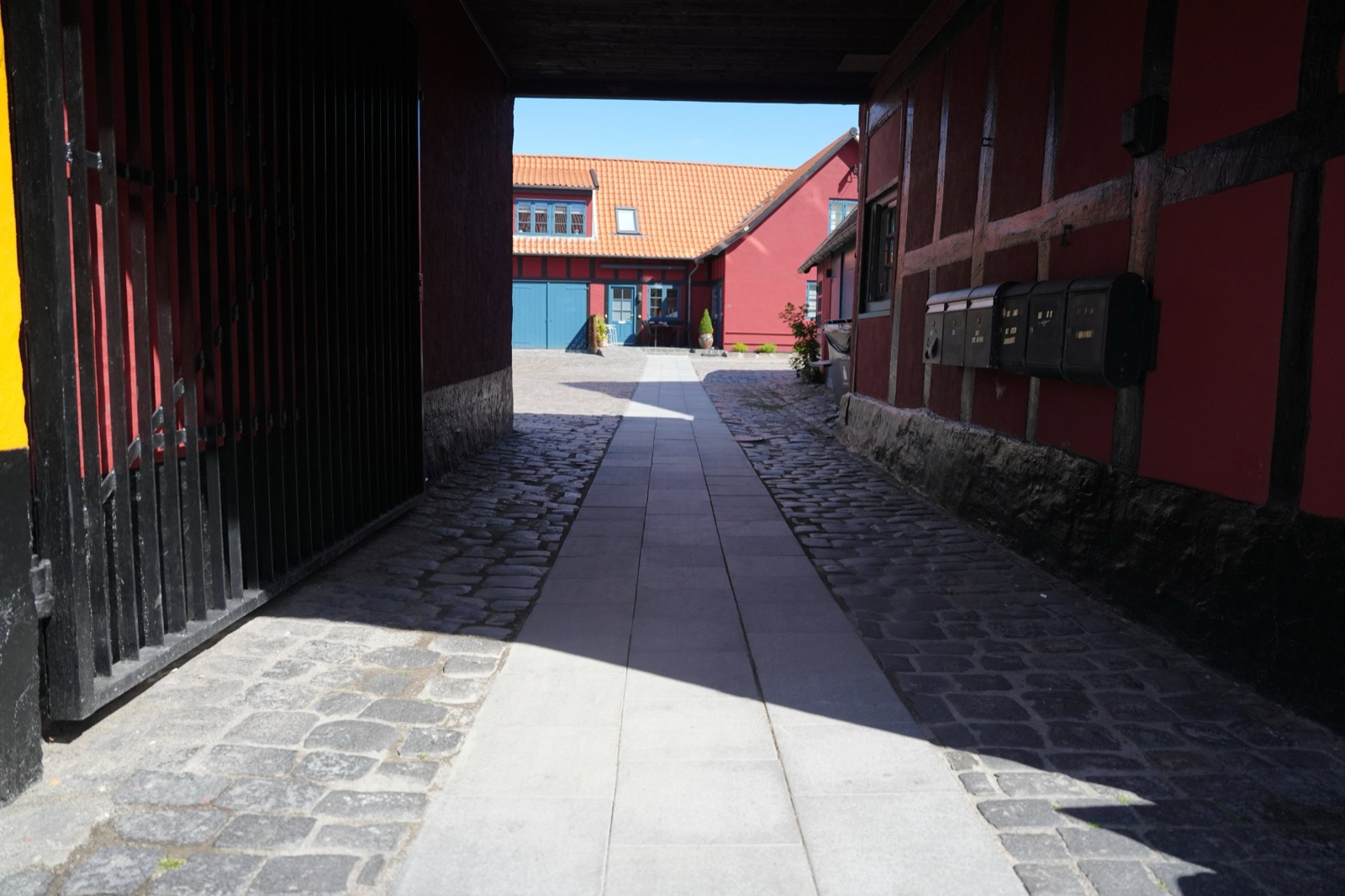 Covered gateway passage with rough cobblestones and a smooth flagstone strip running through the middle