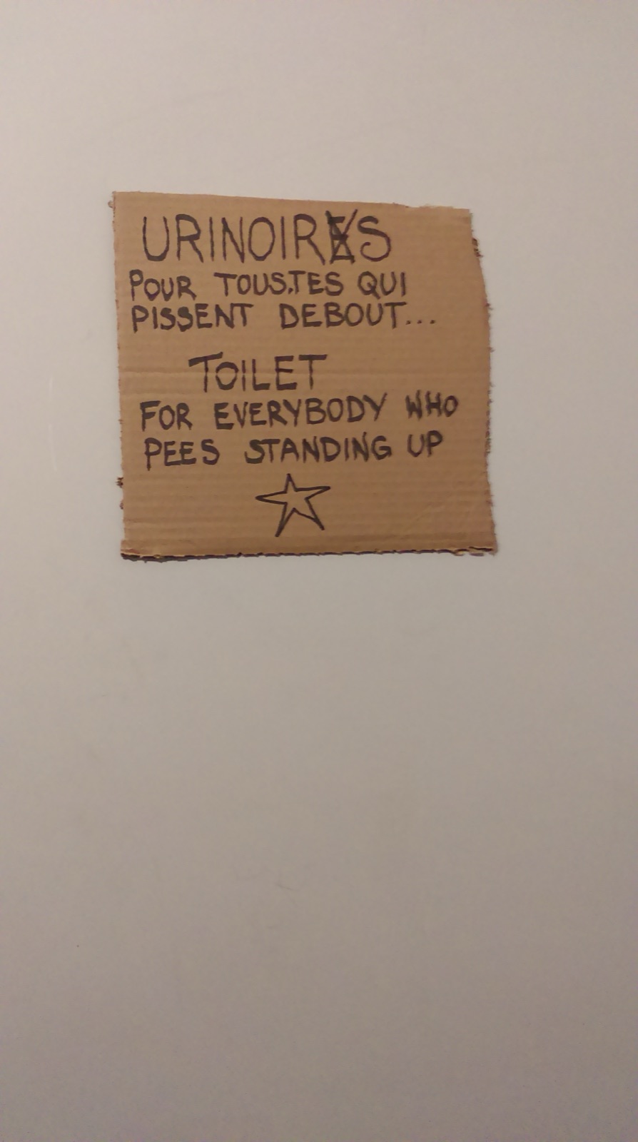 Handwritten toilet sign reading “for everybody who pees standing up”