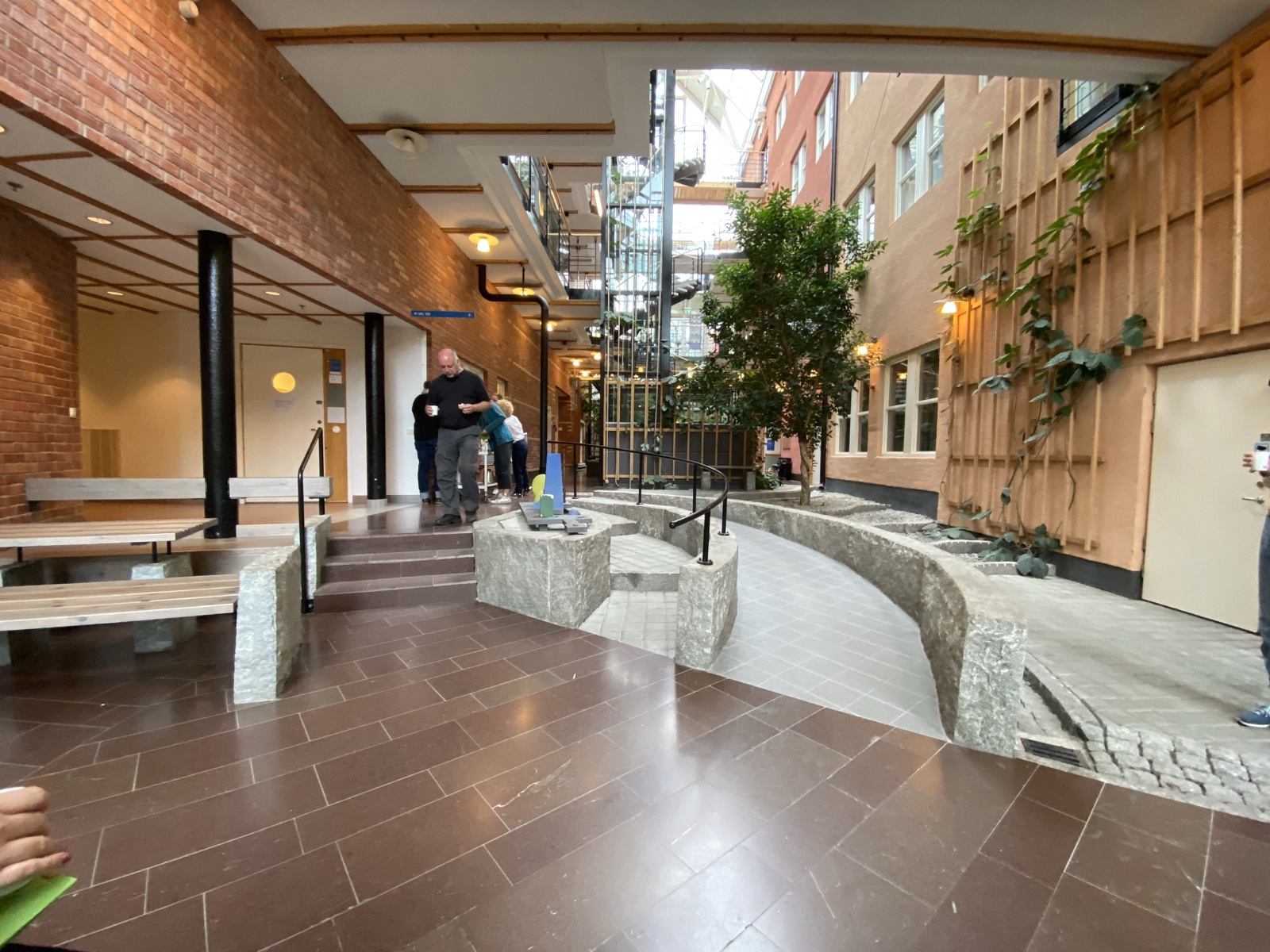 Indoor atrium where central steps and a broad curved ramp handle the same level change side by side
