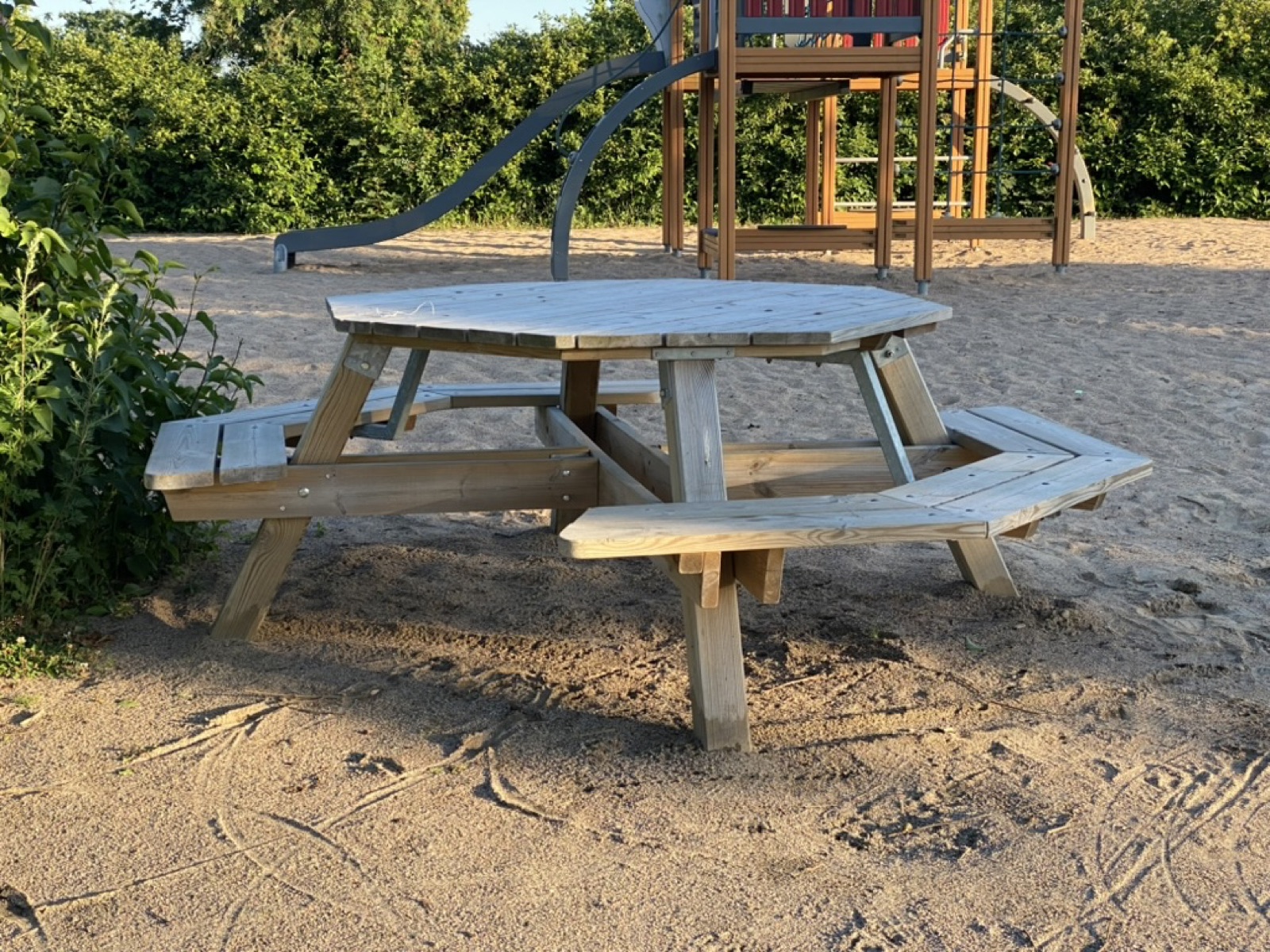 Round picnic table with gaps between the bench sections, in a playground