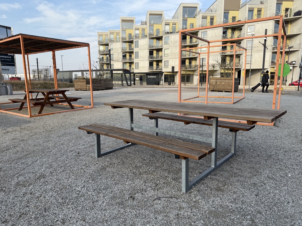 Picnic table on a gravel square where the tabletop extends past the benches, leaving a free open edge