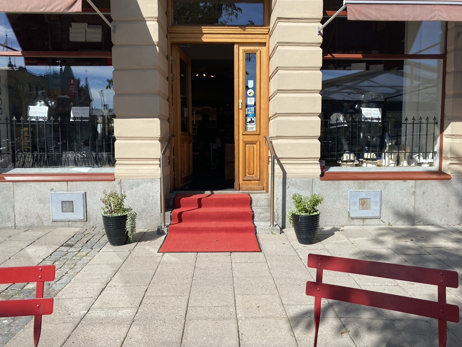 Classic building entrance on a walking street. A wooden door flanked by columns, with a red carpet draped over the steps.