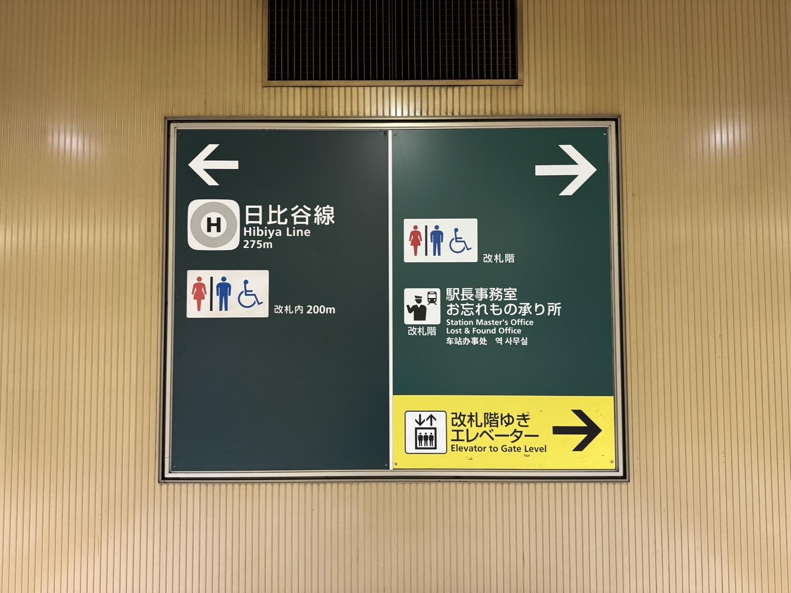 Wayfinding board in the Tokyo metro near the Hibiya Line, with directional arrows, distances, line indicators, and wheelchair and elevator symbols.