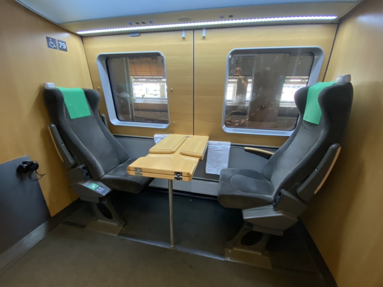 Accessible seating area on a Swedish SJ3000 train, marked with a wheelchair symbol. Two comfortable seats facing each other across a table.