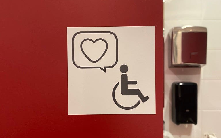 Toilet door with wheelchair and heart.