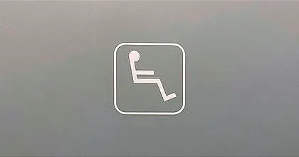 A wheelchair sign on a toilet door in Italy, where someone has peeled off the wheel, leaving only the person visible.