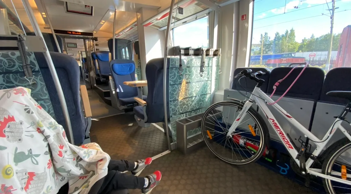 Photo from inside the train, with two contrasting compartments: one for things and persons on wheels and one for “normal/typical” passengers.